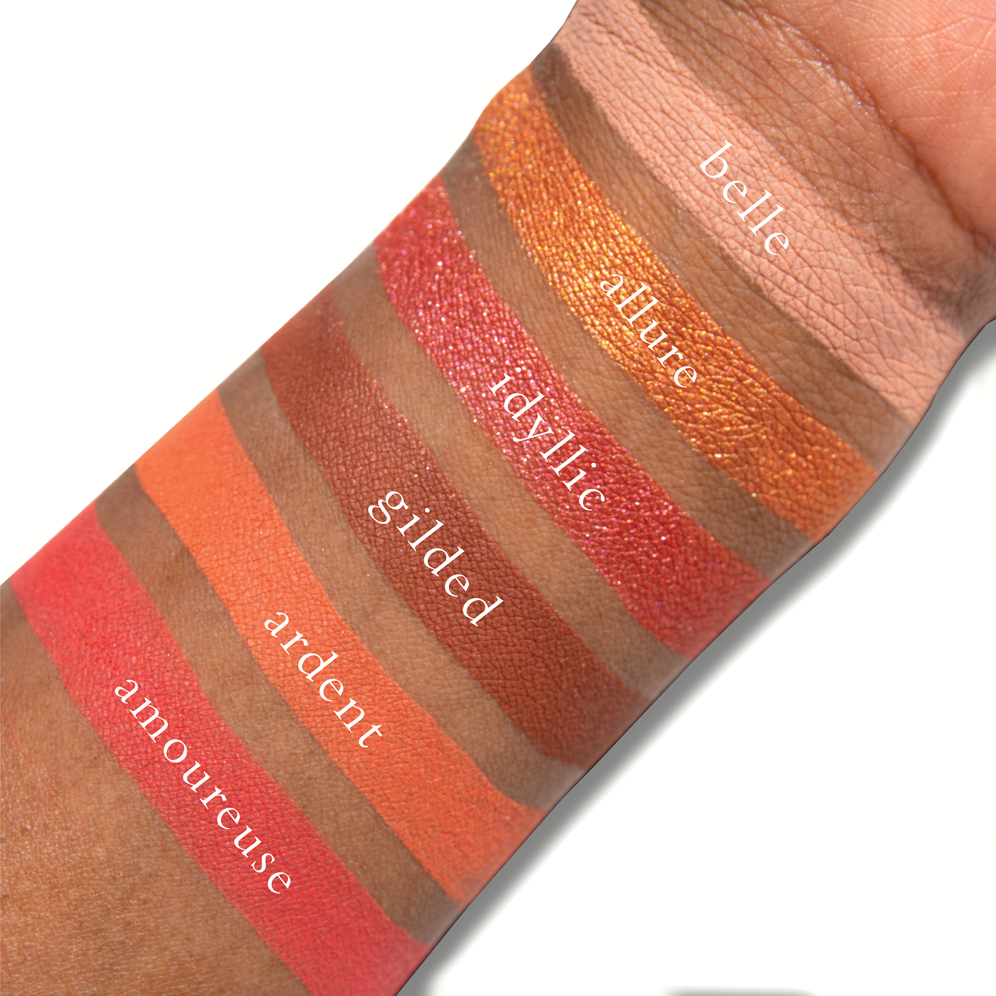Swatches of Fleurette Bisous on deep skin featuring luminous coral, radiant peach, and fresh pink tones with soft matte and shimmer textures.