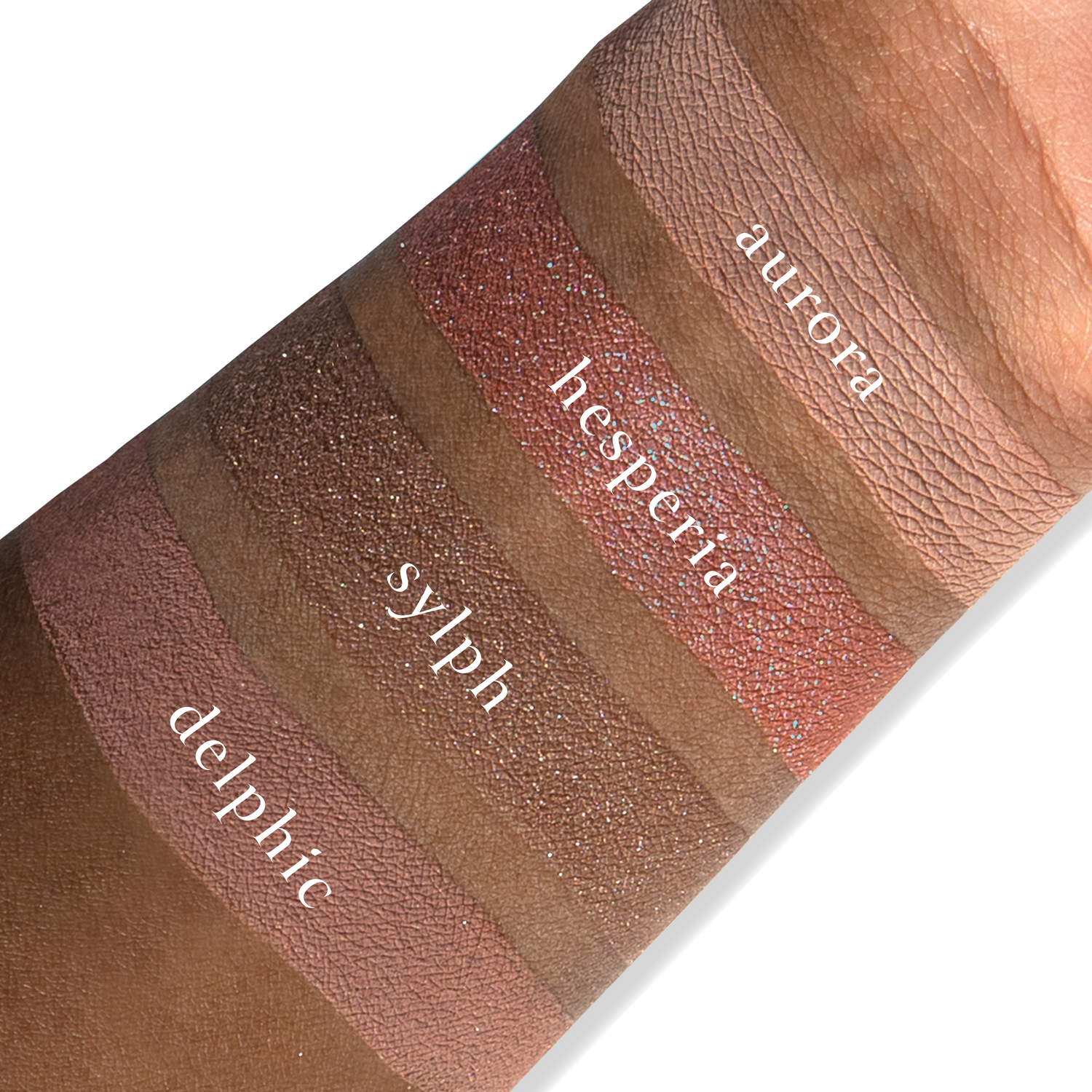Swatches of eyeshadow powders from the Petits Fours - Hesperides palette on deep skin, showcasing timeless rose, mauve, and nude hues.