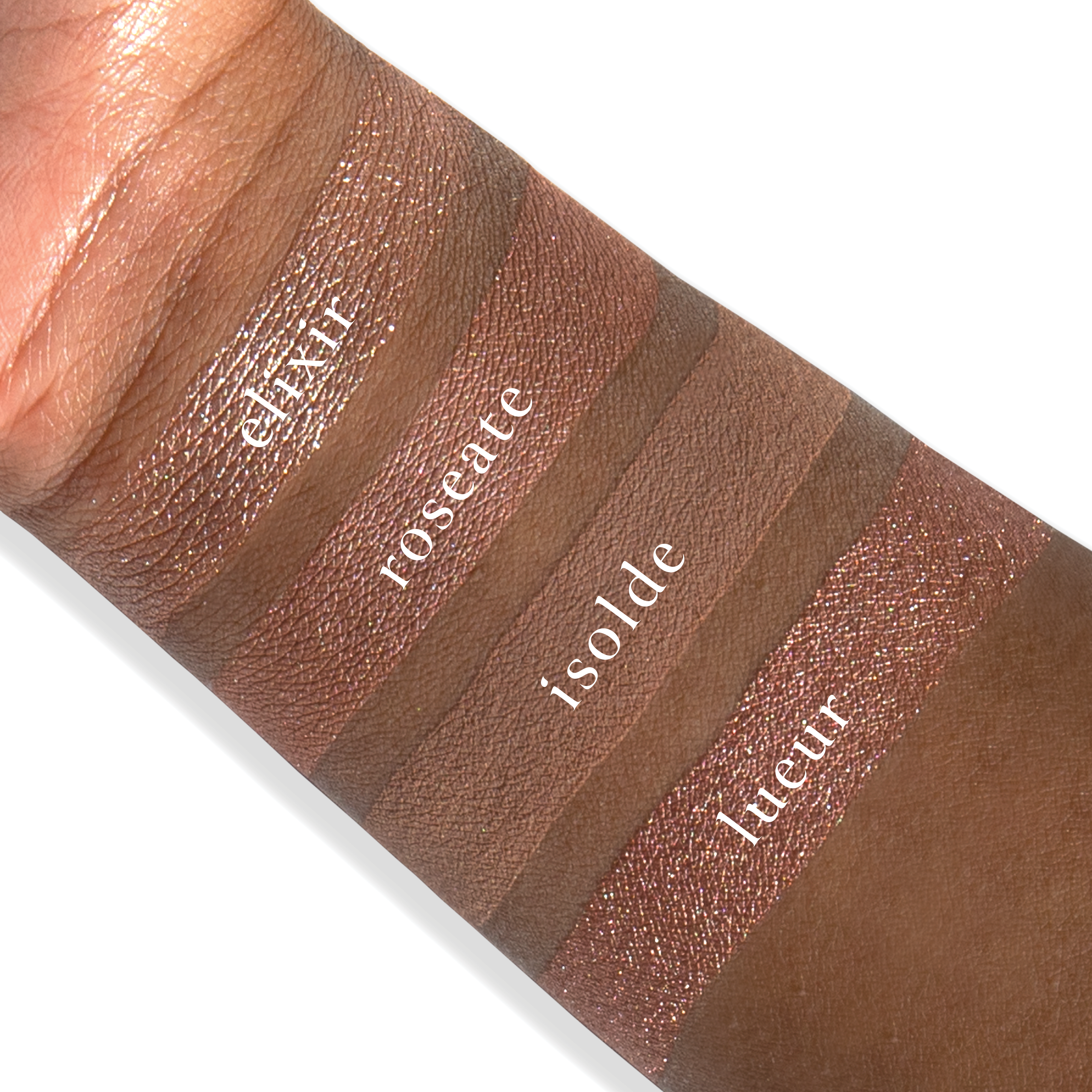 Swatches of eyeshadow powders from the Petits Fours - Isolde palette on deep skin, showing romantic rose, nude shimmer, and soft satin tones.