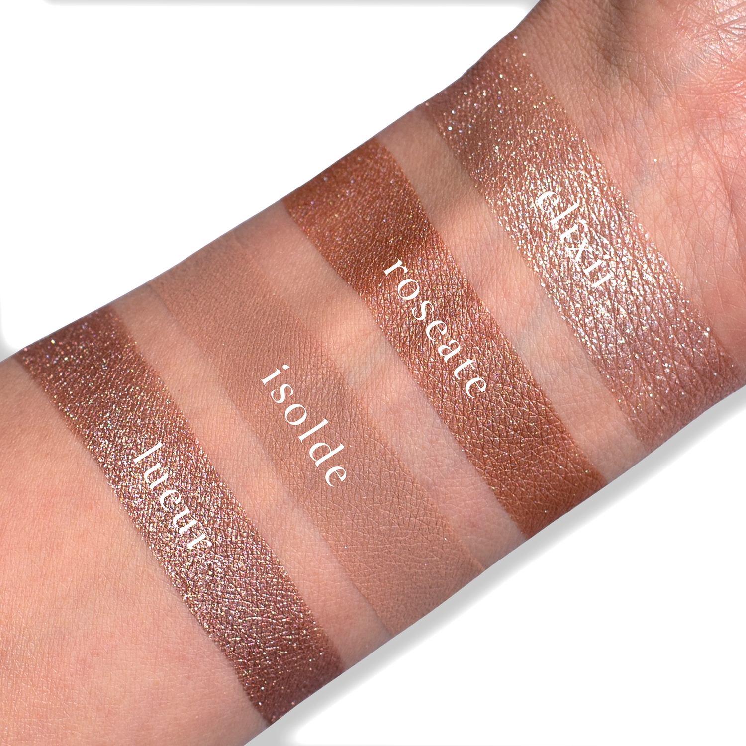 Swatches of eyeshadow powders from the Petits Fours - Isolde palette on fair skin, showing romantic rose, nude shimmer, and soft satin tones.