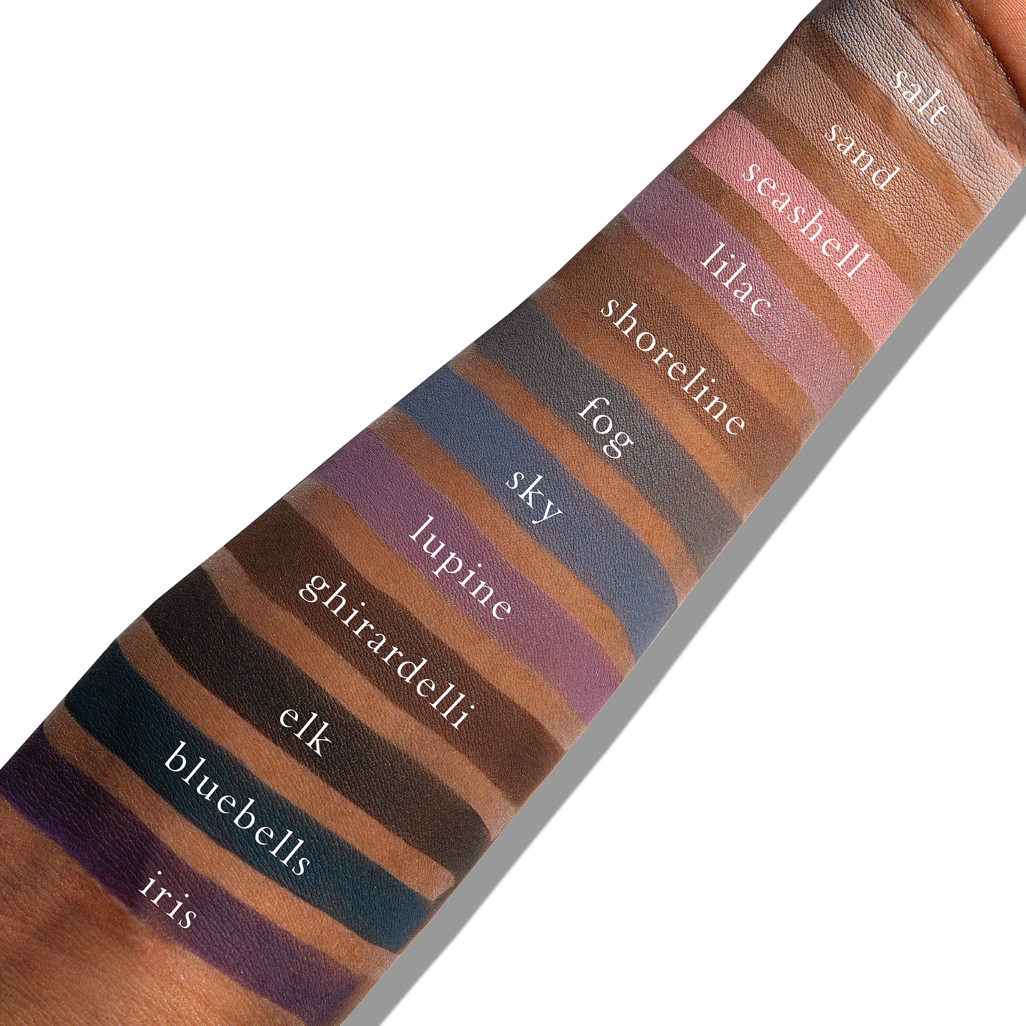 Swatches of cool matte shades like taupe and plum on deep skin, offering soft contour and cool depth.