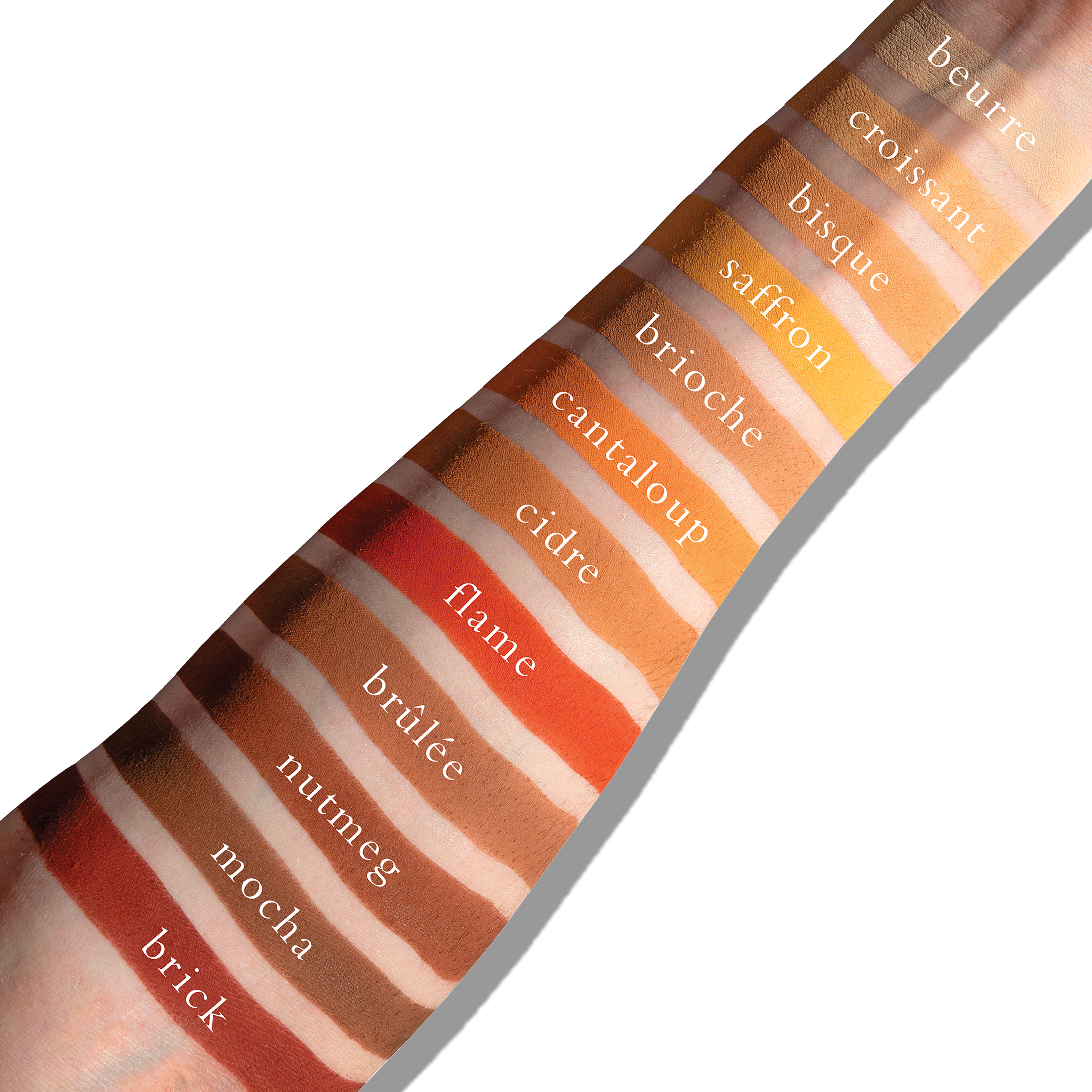 Swatches of warm matte shades like ochre and terracotta on fair skin, showing sculpting and depth on light tones.