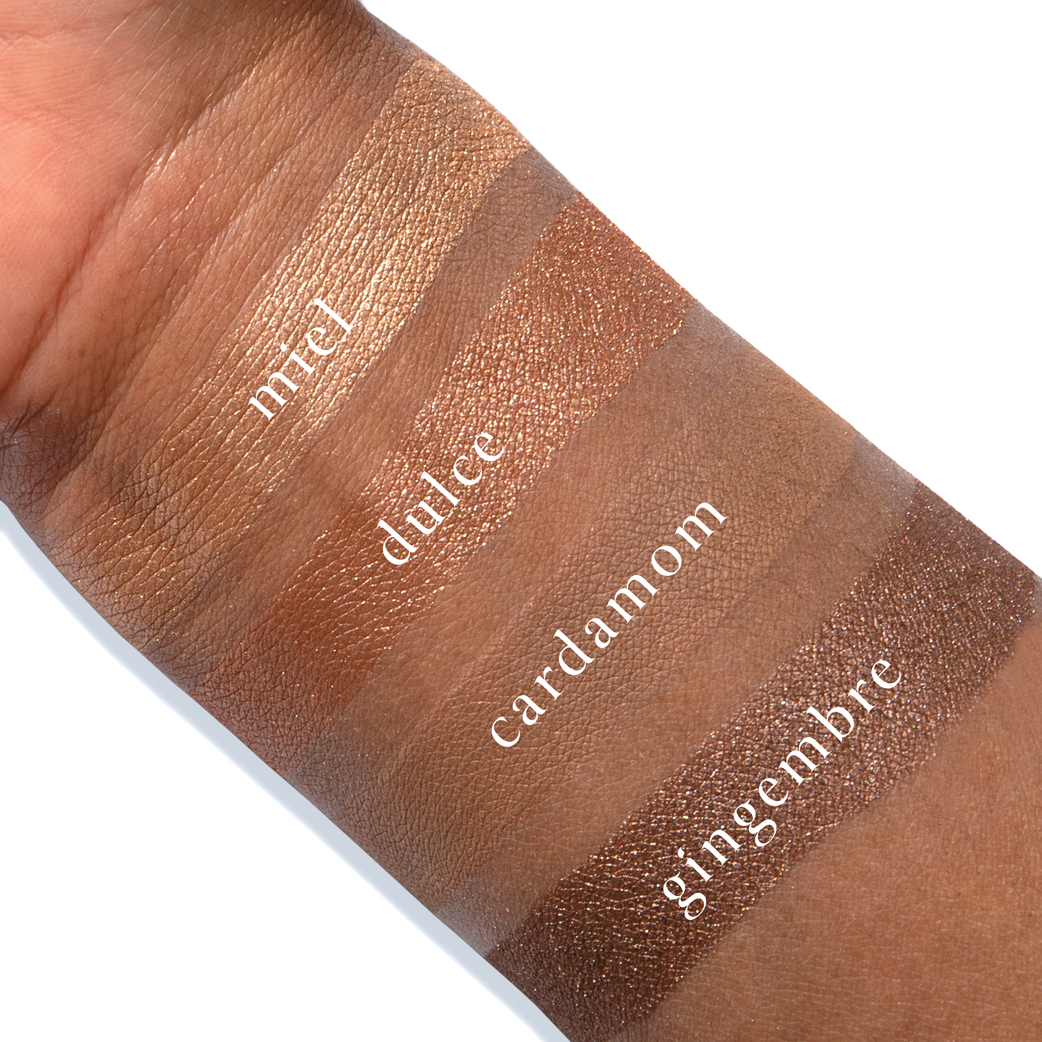 Swatches of Petits Fours Praline Epice on deep skin, featuring golden shimmer, matte spice, and warm taupe.