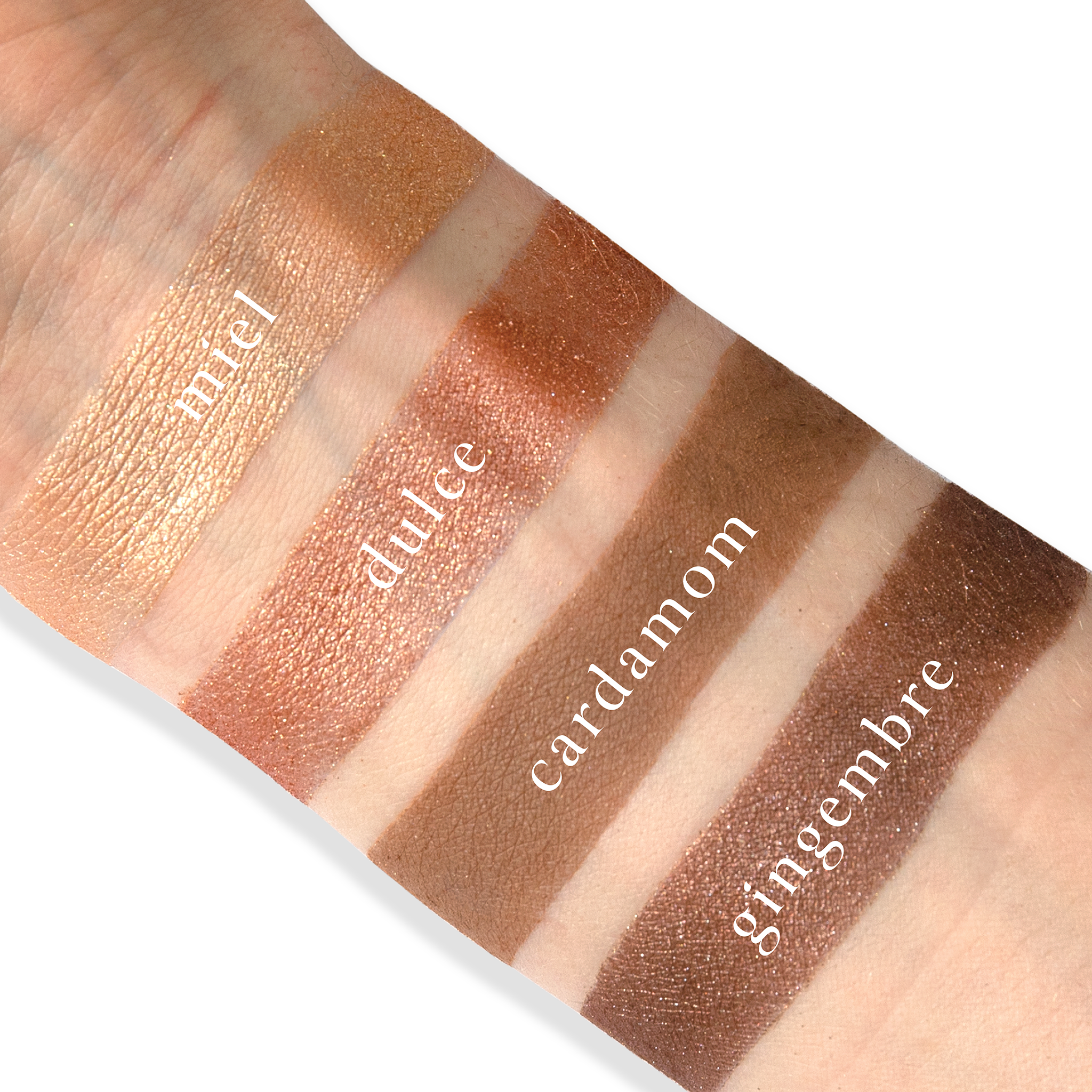 Swatches of Petits Fours Praline Epice on fair skin, showing burnished bronze, soft matte brown, and golden taupe.