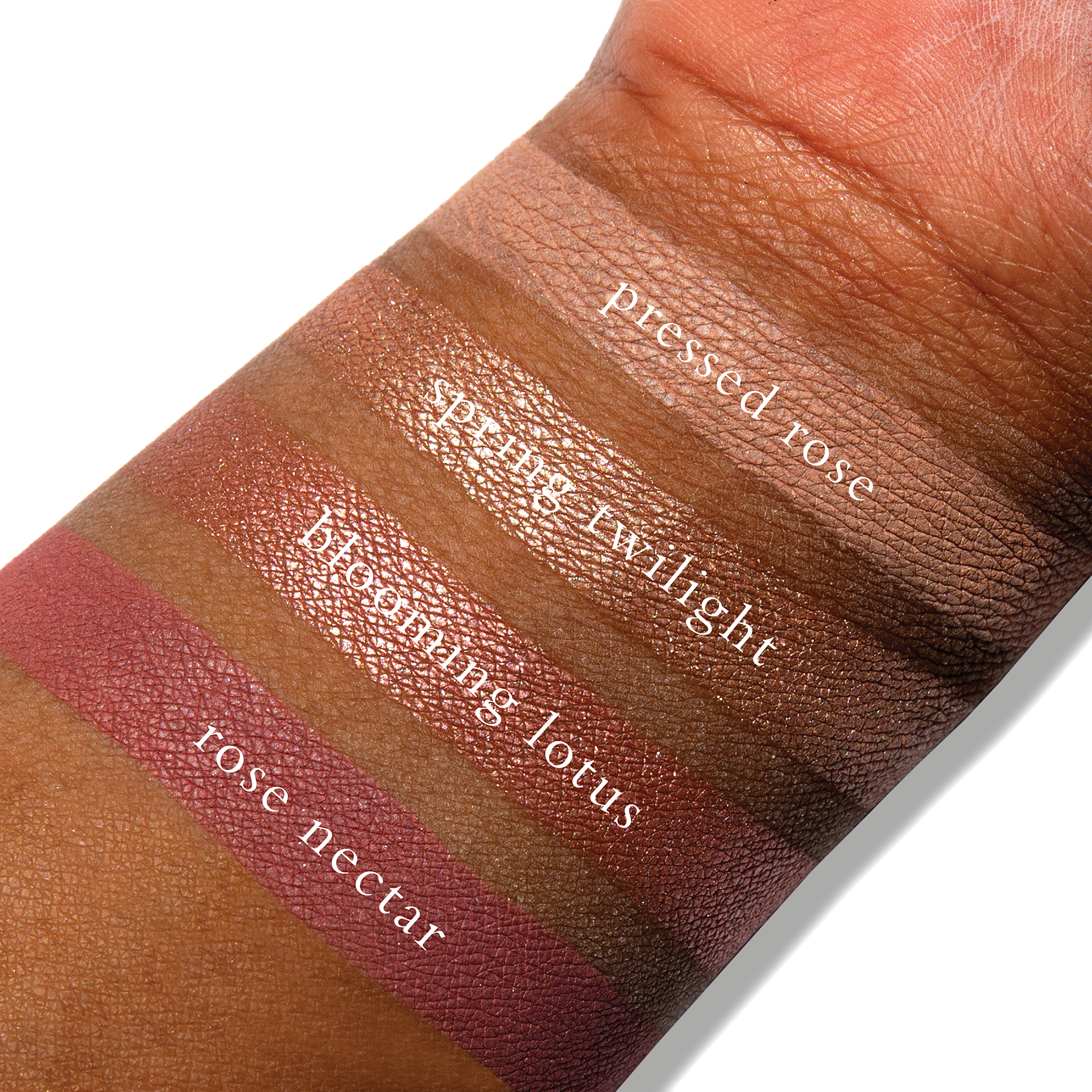 Swatches of blush rose, coral shimmer, and warm pink matte from Rosea Lotus on deep skin tone.