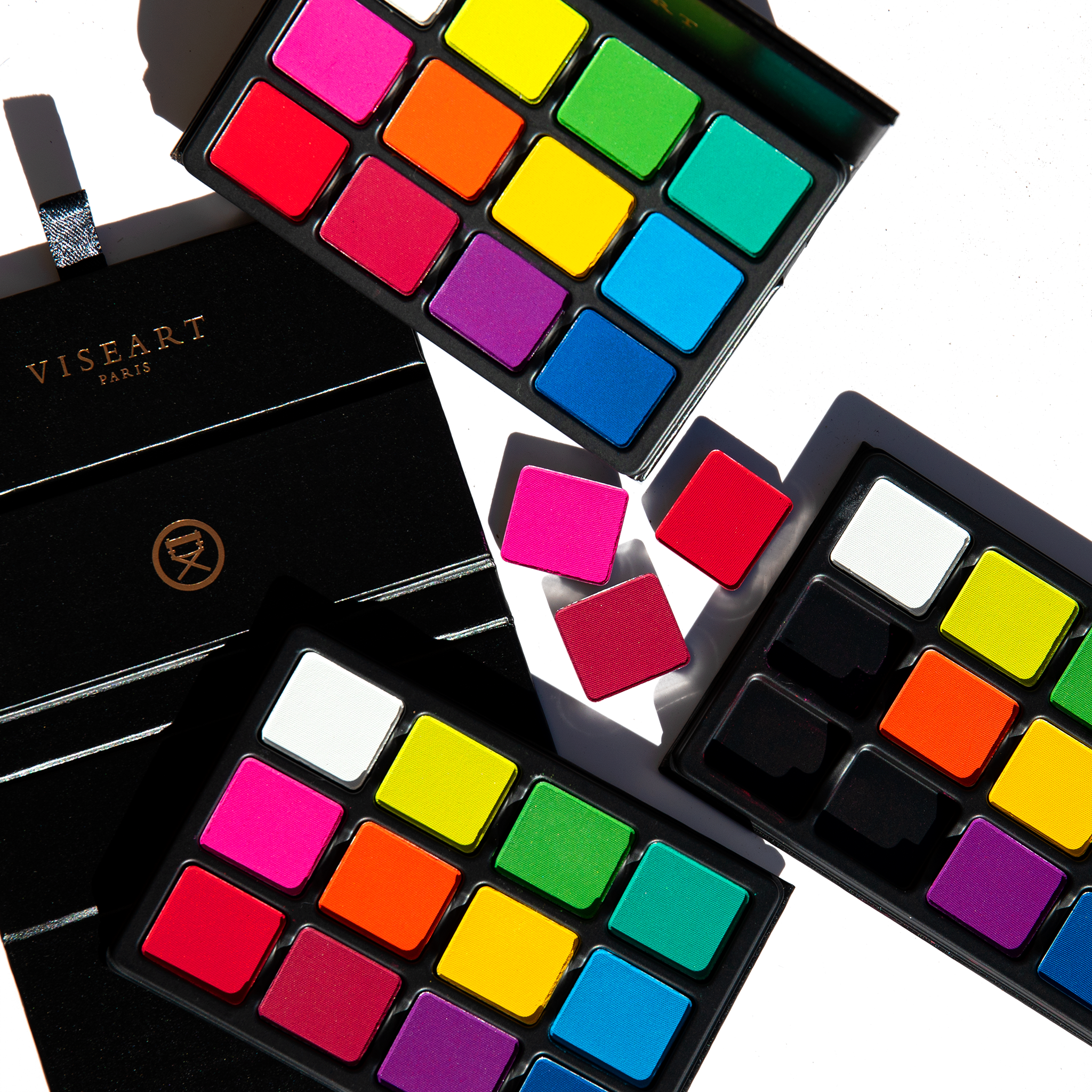 Swatches of bright matte shades on fair skin, from red and violet to yellow and green, showing bold payoff.