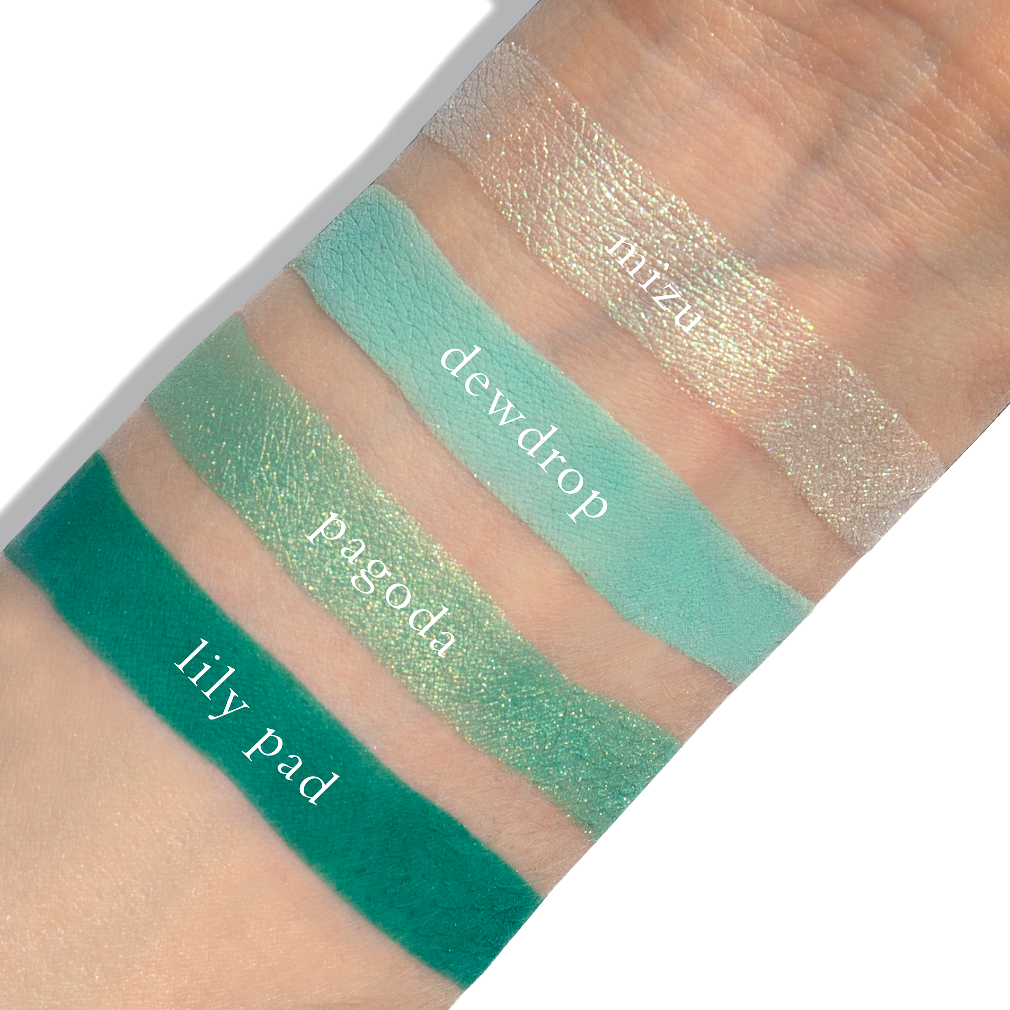 Swatches of aqua shimmer, soft teal, and icy blue from Water Lotus on fair skin tone.