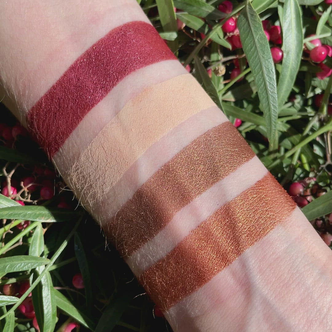 Swatches of Petits Fours Garnet on fair skin, highlighting warm red matte, plum shimmer, and wine satin