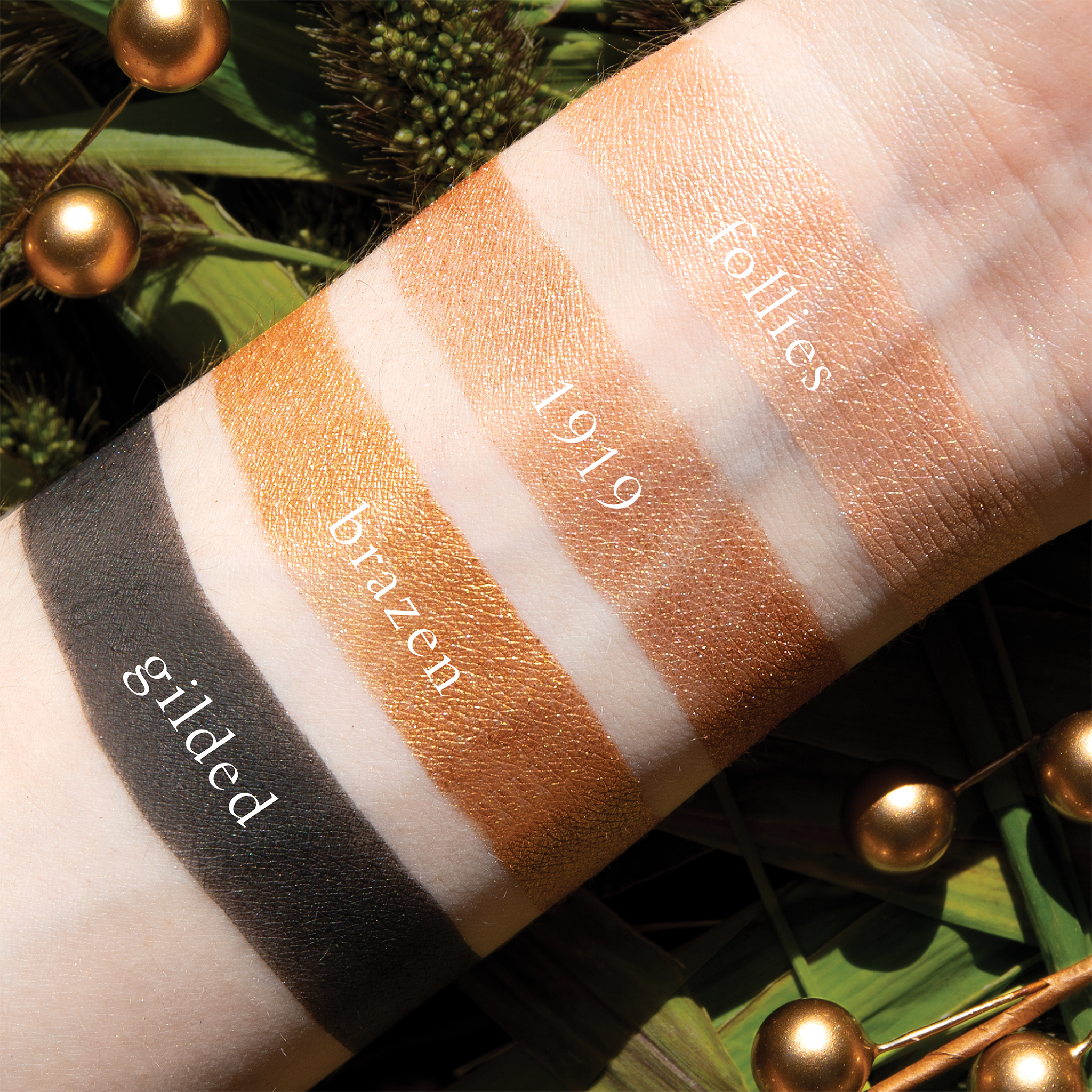 Swatches of Petits Fours Bullion on fair skin, showing radiant gold shimmer, champagne tones, and matte black.
