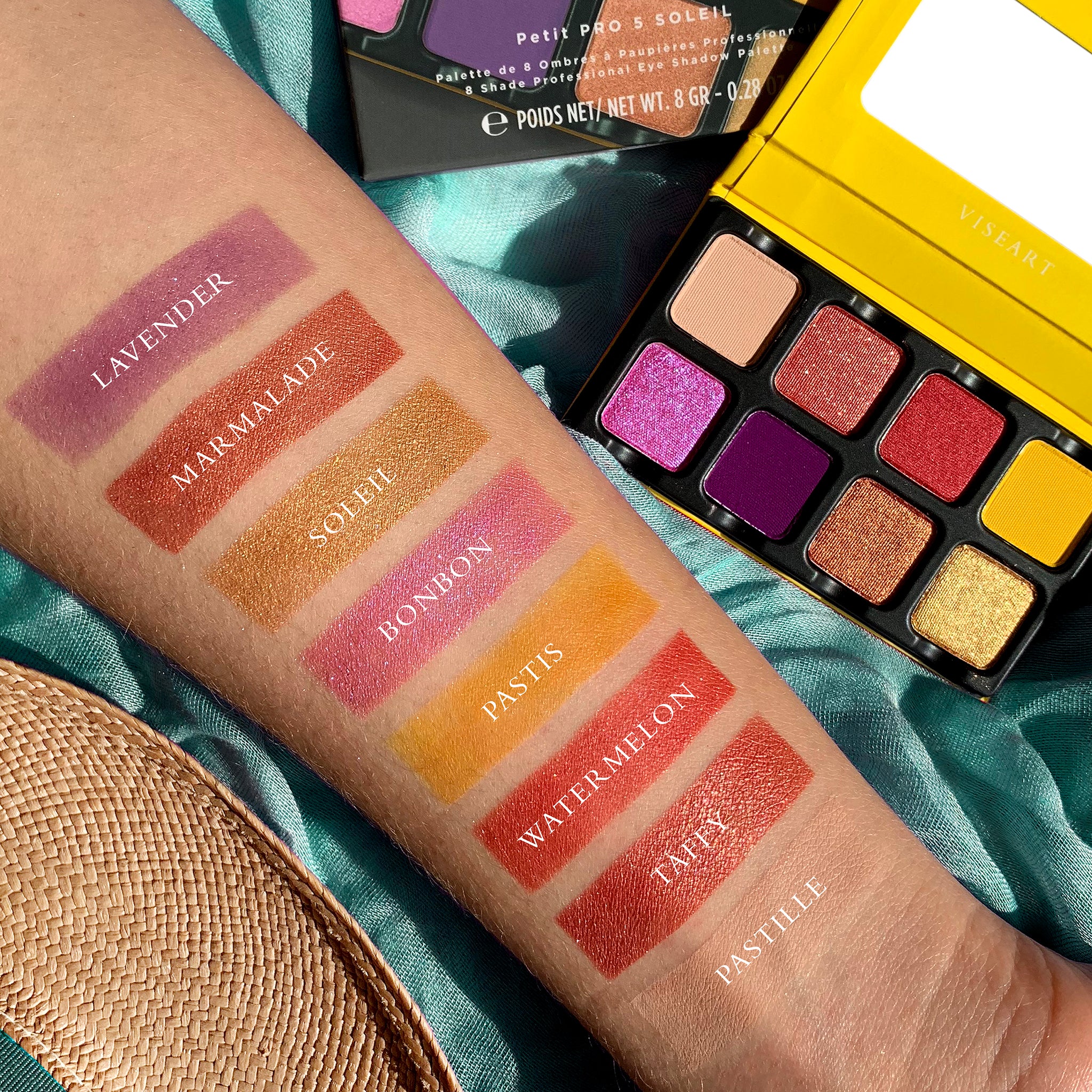 Vibrant swatches of yellow, coral, and lavender shades from Petit Pro Soleil on deep skin tone.