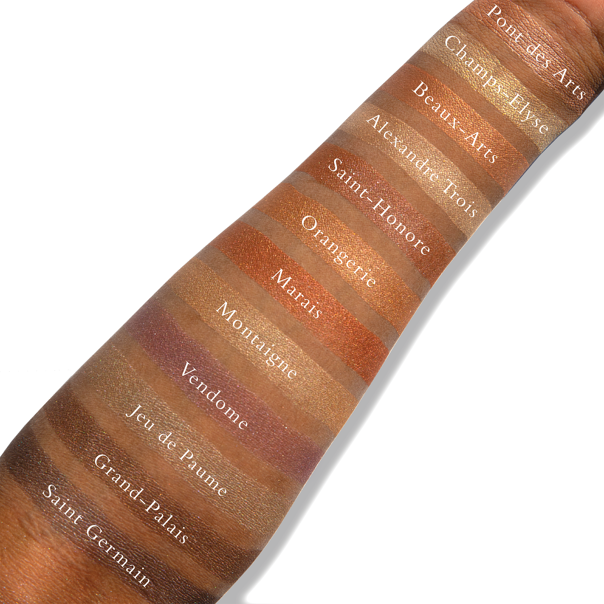 Swatches of powders from the Petites Shimmers Paris Nudes palette on deep skin, showcasing versatile tones for highlighting and shading.