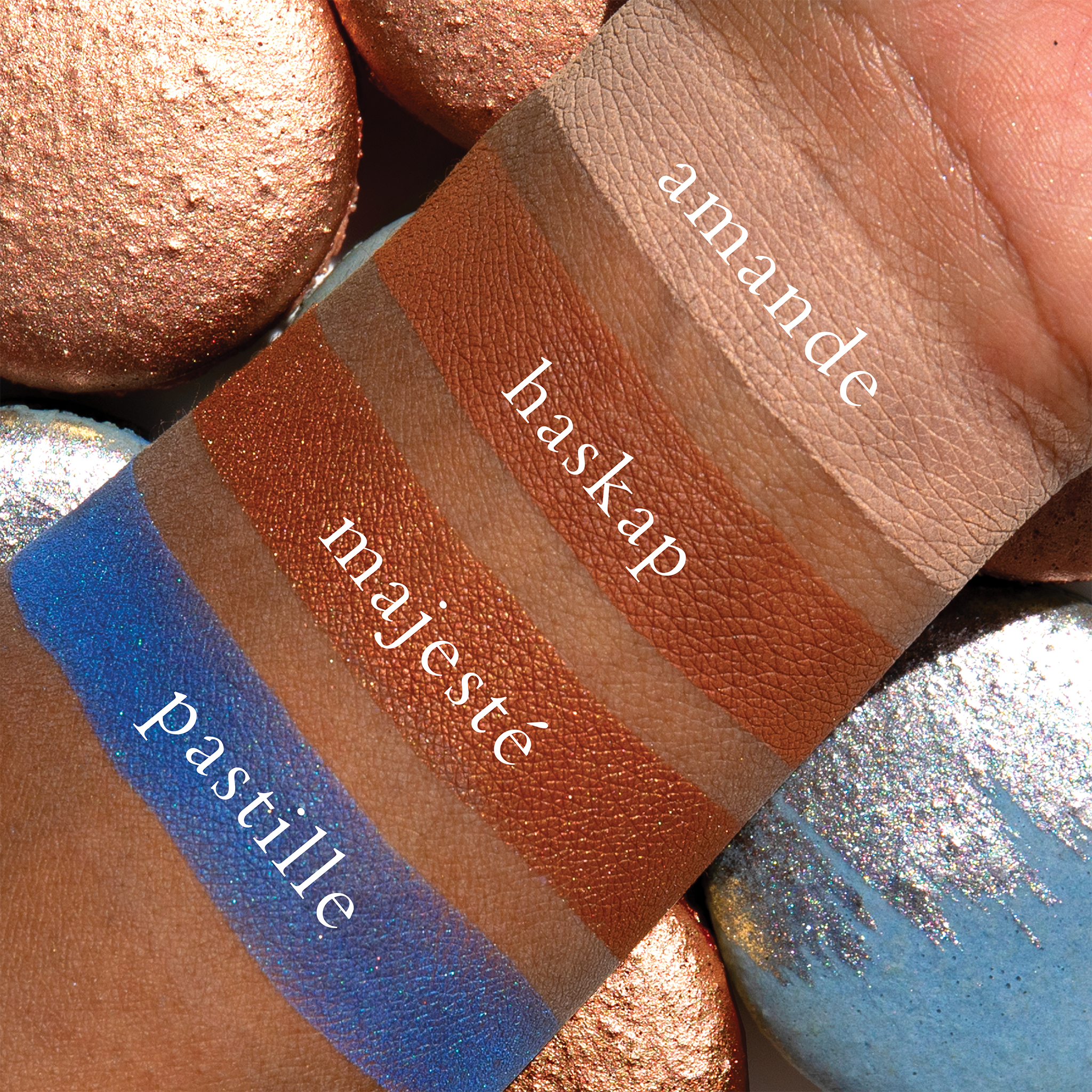 Swatches of Petits Fours Pastille on deep skin, showing vibrant cobalt, burnished caramel, and soft cream.
