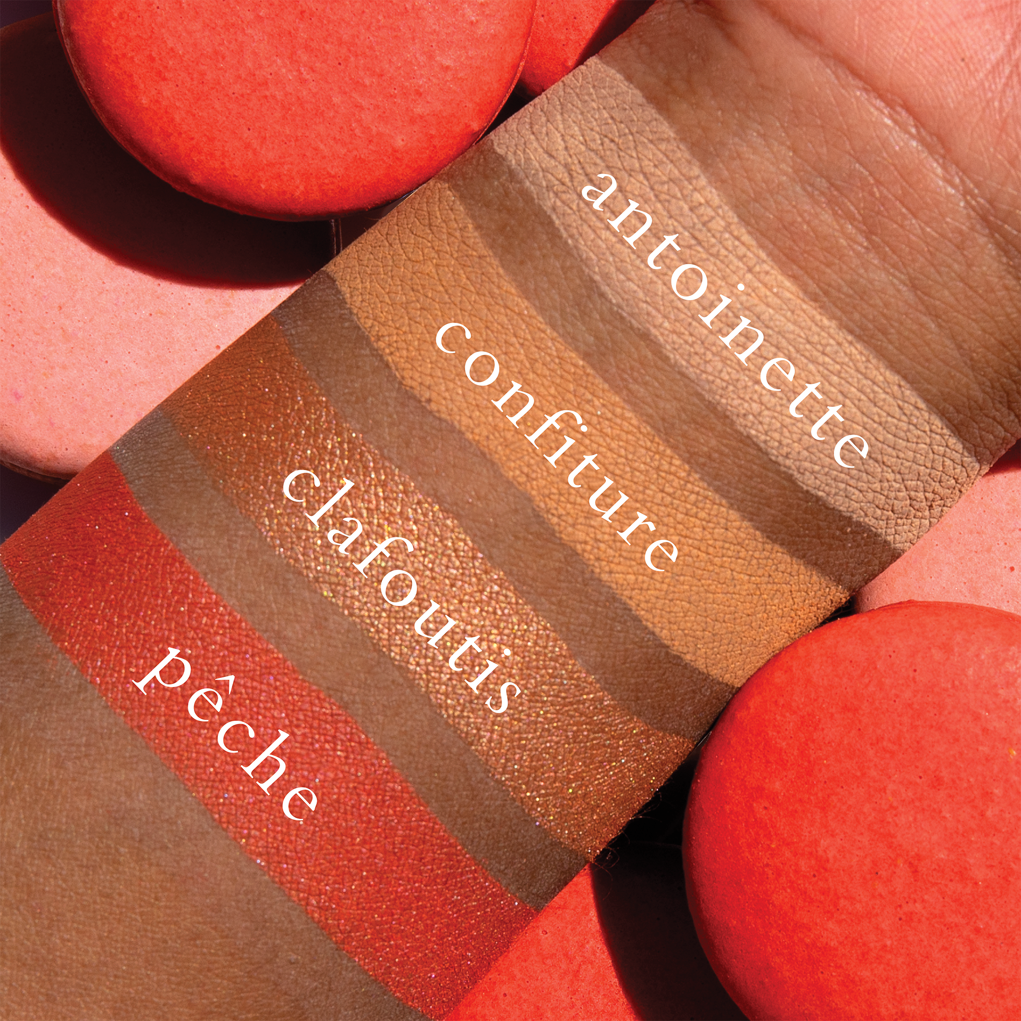 Swatches of golden peach, coral matte, and apricot shimmer from Petits Fours Pêche on deep skin tone.