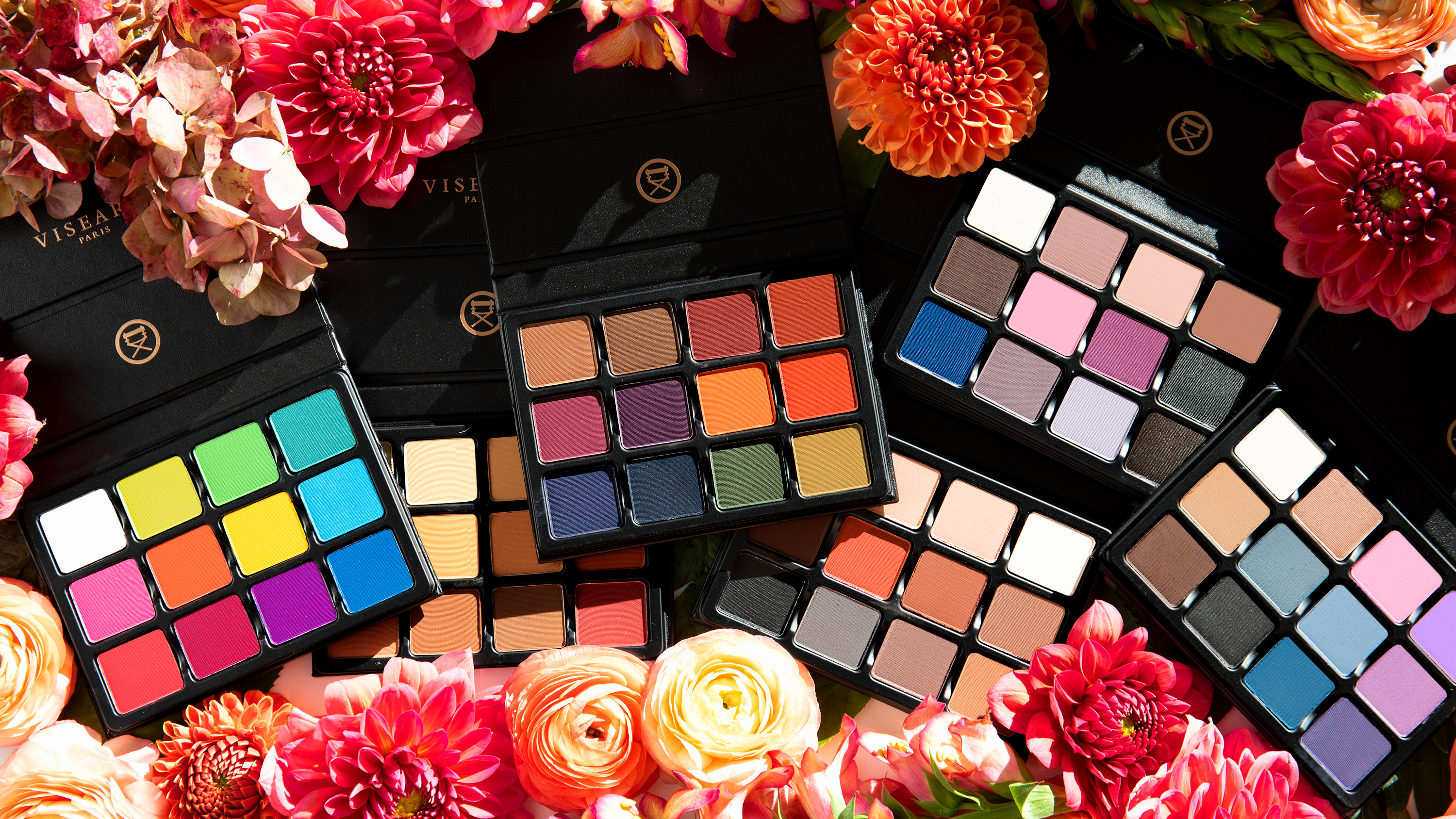Flatlay of cool-toned and smoky neutral eyeshadow palettes inspired by autumn twilight with matte, shimmer, and duochrome finishes in a pro-grade blendable formula.