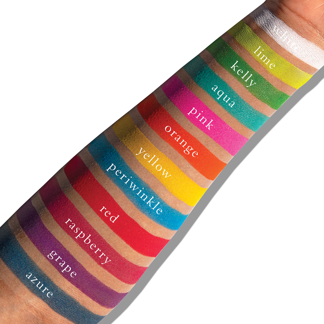 Swatches of vivid matte brights like red, yellow, and blue on deep skin, showing high-impact editorial colour.